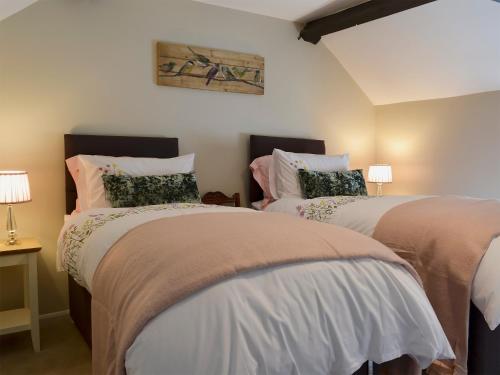 a bedroom with two beds and two lamps at Lowther Cottage in Clifton