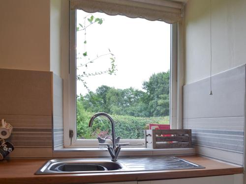 a kitchen sink with a window above a kitchen counter at Ticket Office in Torver