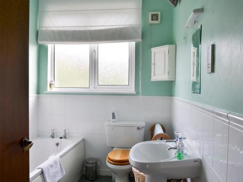 a bathroom with a toilet and a sink and a tub at Bluebells in Strathpeffer