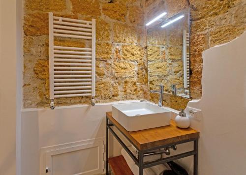 a bathroom with a sink and a stone wall at Isula in Palermo