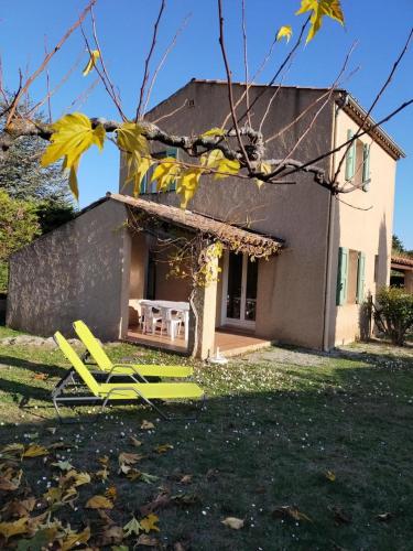 a group of yellow lawn chairs in front of a house at Les lauriers in Moissac-Bellevue