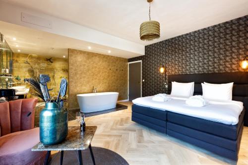 1 dormitorio con 1 cama grande y bañera en Hotel Karsten en Norg