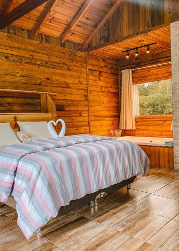 um quarto com uma cama num quarto de madeira em Cabana Furna dos Pôneis em Urubici