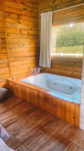 uma banheira num quarto de madeira com uma janela em Cabana Furna dos Pôneis em Urubici