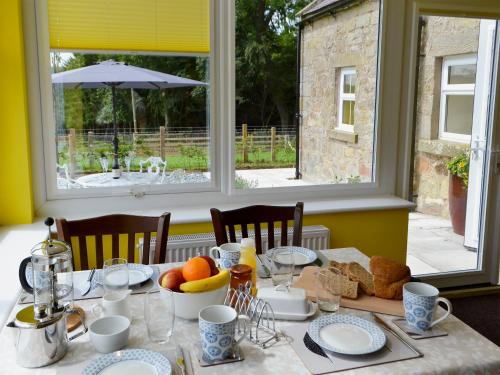a dining room table with a table set with food at Squirrel Cottage in Sharperton