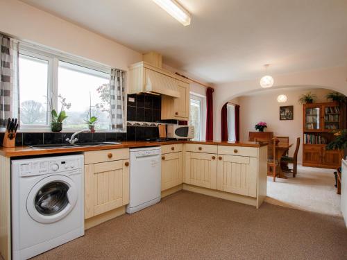 a kitchen with a washer and dryer in it at Orchard Well in Winscombe