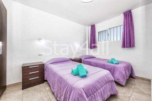 two beds in a room with purple sheets at Apartamento Los Molinos in Playa del Ingles