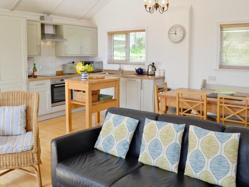 a living room with a couch and a kitchen at Pottery Cottage in Broadway