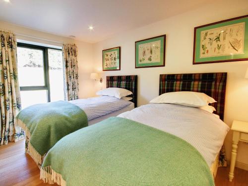 a bedroom with two beds and a window at Phils House in Lairg
