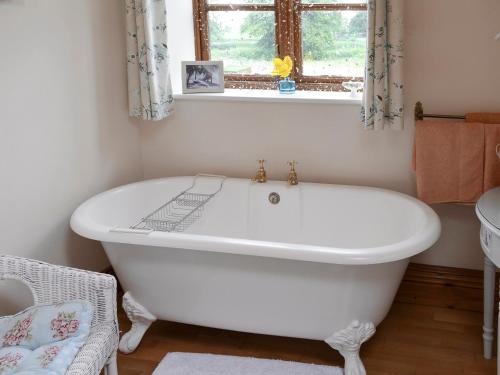 La salle de bains est pourvue d'une baignoire blanche et d'une fenêtre. dans l'établissement Buddileigh Farm, à Betley