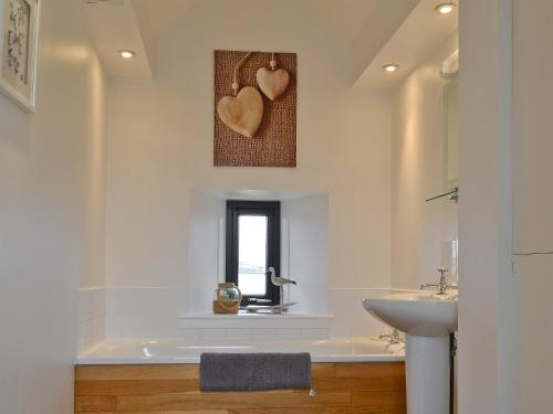 a bathroom with a sink and a window with two hearts on the wall at 7 Greep in Orbost