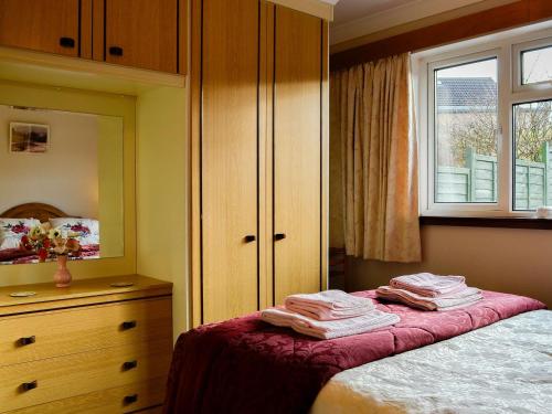 a bedroom with a bed and a dresser and a window at Briar Bank Bungalow in Cockermouth