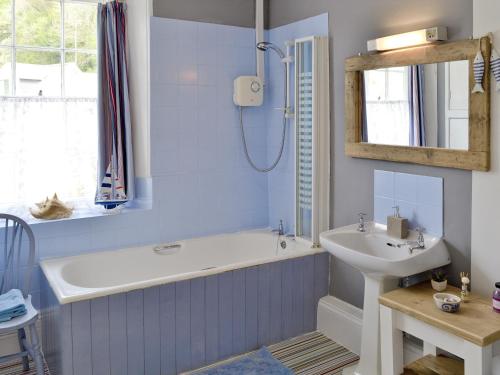 a bathroom with a bath tub and a sink at Yawl House in Uplyme