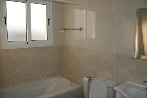a bathroom with a tub and a toilet and a sink at Nissi Villa in Ayia Napa
