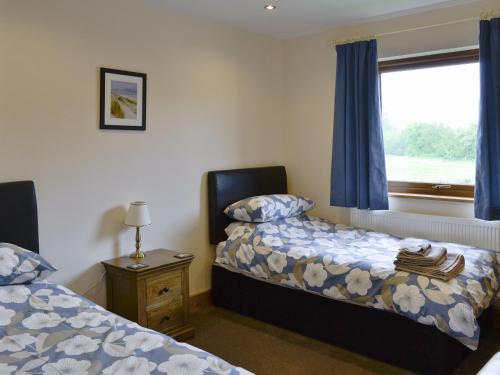 a bedroom with two beds and a window with blue curtains at Willow Lodge in Burgh le Marsh