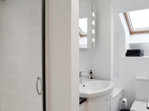 a white bathroom with a sink and a mirror at Seascape in New Quay