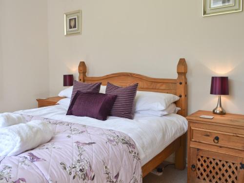 sypialnia z łóżkiem z fioletowymi i białymi poduszkami w obiekcie Grey Cottage w mieście Pentraeth