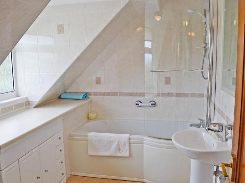 y baño blanco con lavabo y bañera. en Grey Cottage, en Pentraeth