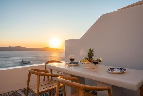 a table with two glasses of wine and a view of the ocean at Inspire Santorini Luxury Villas in Fira