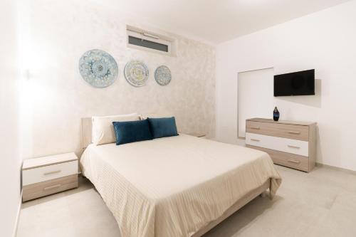 a white bedroom with a large bed and a tv at Pietra Fiorita Dimora in Conversano