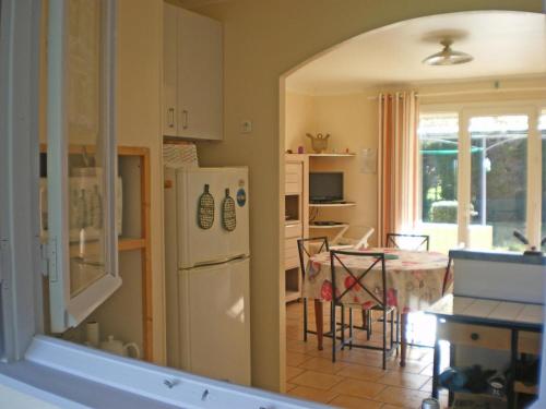une cuisine avec une table et un réfrigérateur blanc dans l'établissement Jolie maison avec terrasse, au Luc