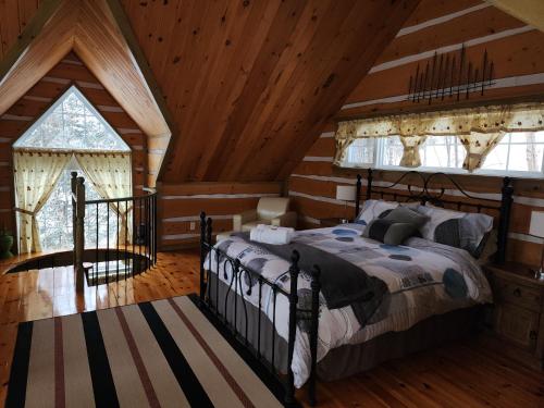 a bedroom with a bed in a room with wooden ceilings at Domaine Rivière Sacacomie in Saint-Alexis-des-Monts