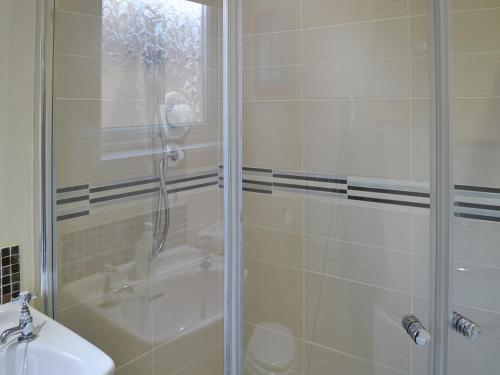 a bathroom with a shower and a sink at 61 Longstone Close in Beadnell