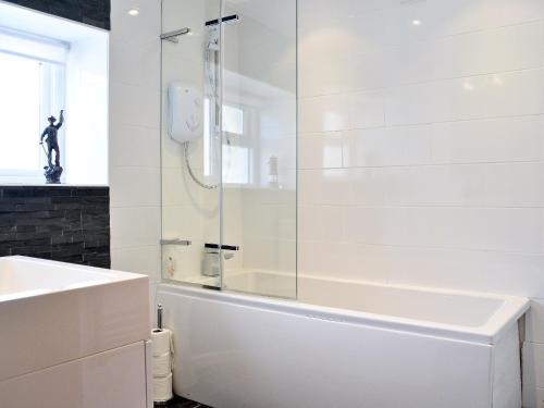 baño blanco con ducha y lavamanos en Trem-y-don Cottage, en Trevine