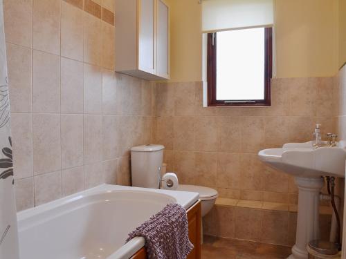 a bathroom with a tub and a sink and a toilet at Helm View in Windermere