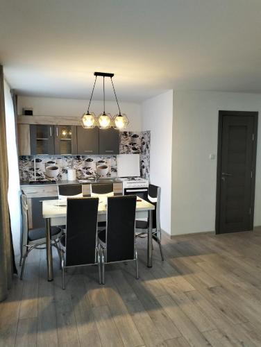 a dining room with a table and chairs and a kitchen at Kub A - 15min de Toplita in Sărmaş