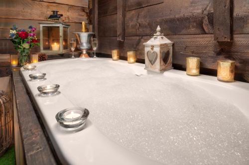 a bath tub with candles and candles on it at The Cowshed at Cheshire Boutique Barns in Nantwich