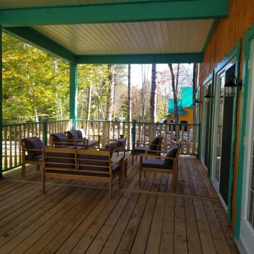 a deck with chairs and tables on a house at Domaine Rivière Sacacomie in Saint-Alexis-des-Monts