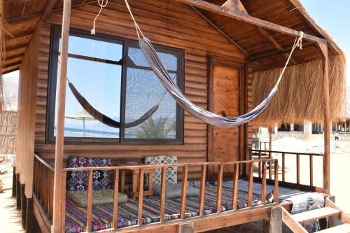 a log cabin with a hammock in front of a window at Shanty beach camp suer in Nuweiba