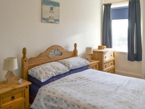 a bedroom with a bed and two dressers and a window at The Lobster Pot in Amble