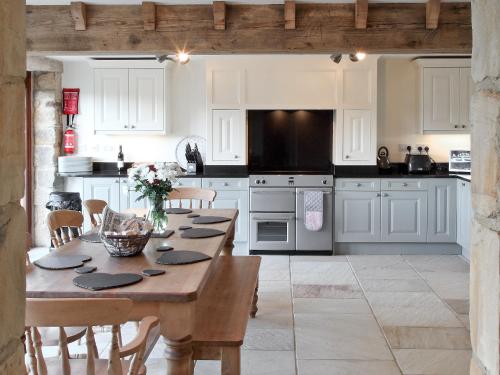 uma cozinha com armários brancos e uma mesa de madeira em Mortar Barn em Stainsacre