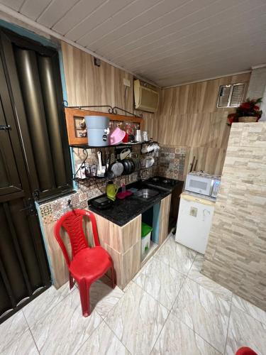 uma pequena cozinha com uma cadeira vermelha e um fogão em Kitnets com AR Condicionado na Praia em Salvador