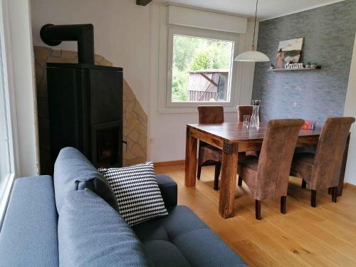 a living room with a blue couch and a dining room table at Ferienhaus Glücksmomente in Möhnesee