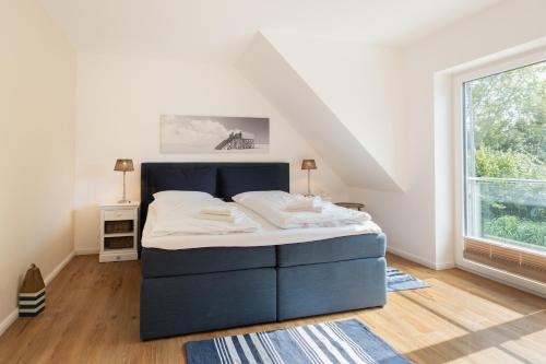 a bedroom with a blue bed in a attic at Ferienhaus DHH SKILLEHUS in Tating