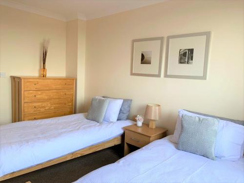 a bedroom with two beds and a dresser at Cosy 2 bed flat near train station Basingstoke with FREE Parking! in Basingstoke