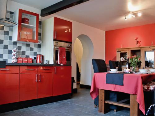 KidwellyにあるBont Cottageのキッチン(赤いキャビネット、ピンクのテーブルクロス付きのテーブル付)
