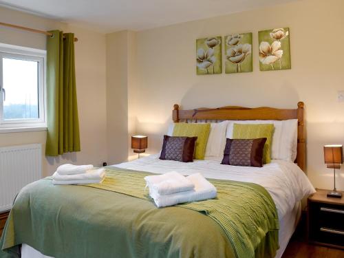 a bedroom with a large bed with towels on it at Bont Cottage in Kidwelly