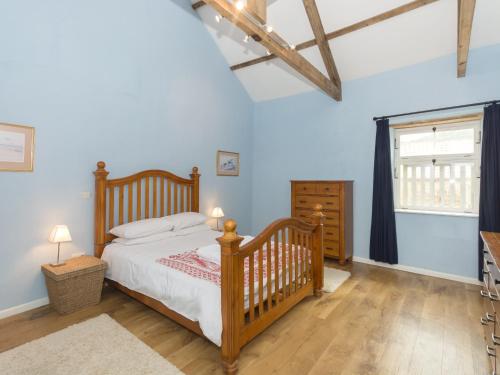 a bedroom with a wooden bed and a window at Ingleby Barn - 27946 in Battersby
