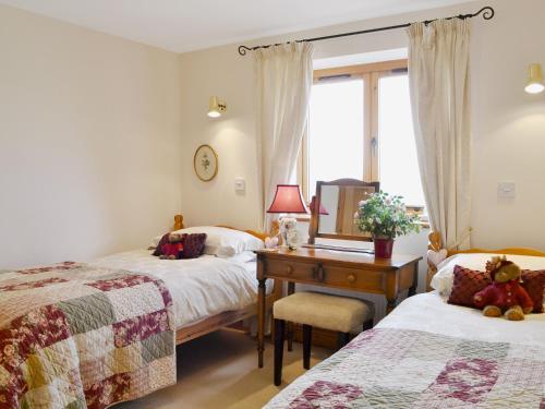 a bedroom with two beds and a desk with a mirror at Ellen Cottage in Ireby