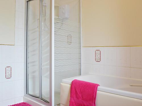 a bathroom with a shower and a white tub at Ty Coch Cottage in Dihewid