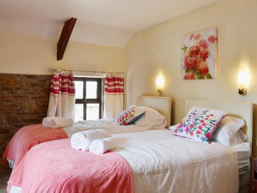 two beds in a room with a window at Ty Coch Cottage in Dihewid