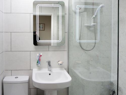 een witte badkamer met een wastafel en een douche bij Hydrangeas in Malborough