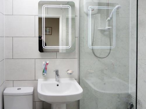 a white bathroom with a sink and a shower at Hydrangeas in Malborough