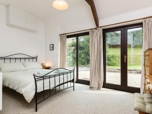 a bedroom with a bed and sliding glass doors at Bramble Cottage in Radstock