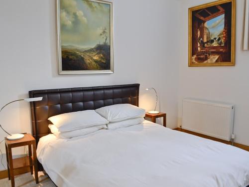 a bedroom with a bed with a painting on the wall at Ammonite Cottage in Beaminster