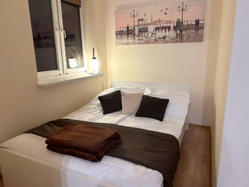 a bedroom with a bed with white sheets and black pillows at Apartament w górach in Mszana Dolna